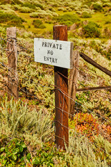 Private No Entry sign on metal fence by spring field