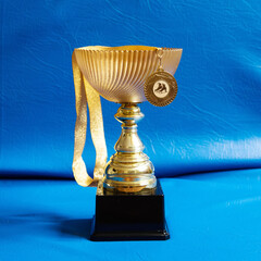 Winner cup with gold medal on blue background. Figure skating.
