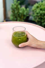 Female hand holding iced matcha drink.
