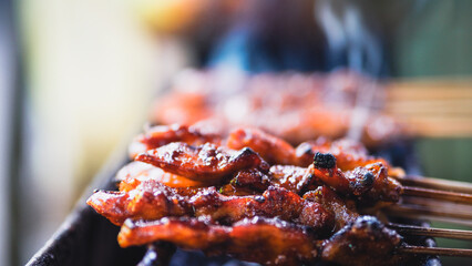 Chicken Satay being grilled on grilling place with charcoal and make some smokes