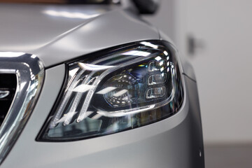 Close-up headlights of a modern silver color car. Detail on the front light of a car. Modern and...