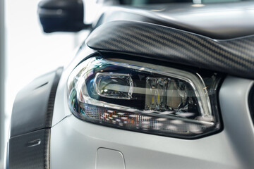 Close-up headlights of a modern silver color car. Detail on the front light of a car. Modern and expensive car concept. The car is in the showroom. Automotive concept. Classic silver color. LED light