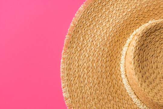 Summer apparel items. Top view of straw sunhat isolated on a pink background. Summer beach vacation concept.