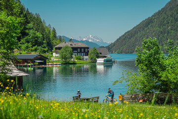 Ostufer or south bank at weissensee austria, beautiful alpine lake with visible village and boat...