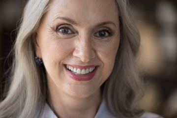 Close up optimistic beautiful middle-aged woman looking at camera, having wide charming smile...