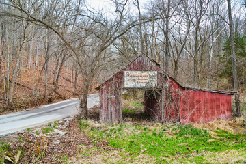Red barn with vintage sign next to road in early spring