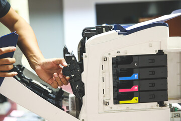 Technician hand open cover photocopier or photocopy to fix paper jam and replace ink cartridges for scanning fax or copy document in office workplace.