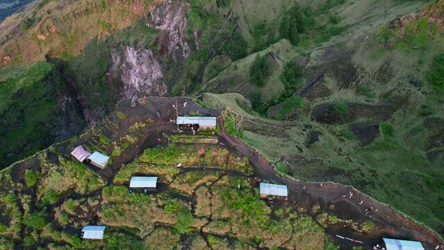 aerial top down of tourists at the cliff of Mount Batur volcano crater rim during sunrise in Bali Indonesia