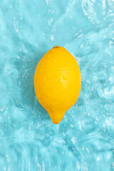 Fresh ripe lemon in blue calm water with splashes and waves.