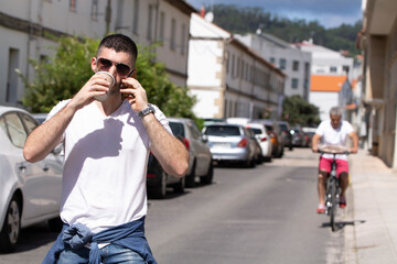 man with sunglasses on the street with phone and coffee to go