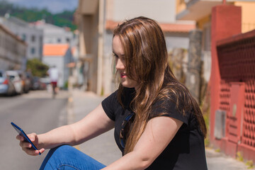 relaxed woman sitting on the street with mobile phone