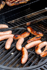 Pork sausages being turned with tongs on a gas barbecue.  Outdoor cooking concept