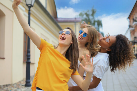 Three cute young girls friends having fun together, taking a selfie at the city.