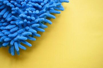 Yellow and blue background. Fluffy blue floor cloth and yellow dust cloth. Home cleaning.