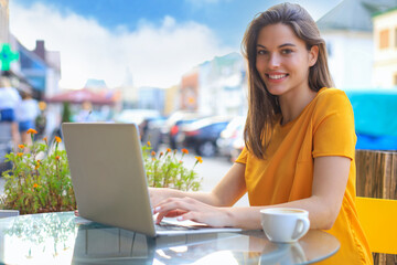 Smiling woman using laptop in cafe. Concept of entrepreneur, businesswoman, freelance worker.