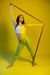 sports girl in the studio in fashionable sportswear. blue and yellow background. sport concept. sport, healthy lifestyle. fitness. colored light. beautiful model. strength and motivation.