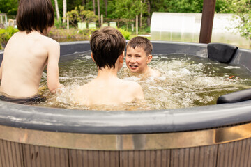Boy have fun in Barrel Hot Tubs, enjoying summer holidays. Wooden bathtub with a fireplace to burn wood and heat water