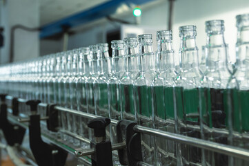 Production line transports empty glass bottles for alcohol
