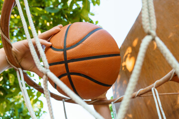 close view of hands throwing a ball into a basketball basket, teenage boy playing at home in the backyard, outdoor activities on summer vacation