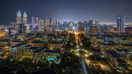 Fototapeta na wymiar Skyscrapers in Barsha Heights district and low rise buildings in Greens district aerial night timelapse.