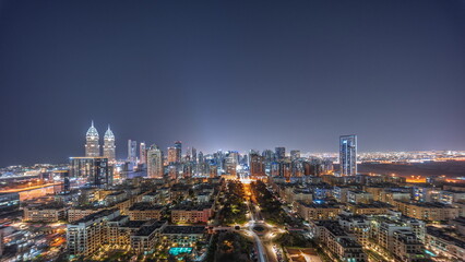 Panorama of skyscrapers in Barsha Heights district and low rise buildings in Greens district aerial night timelapse.