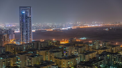 Skyscrapers in Barsha Heights district and low rise buildings in Greens district aerial night timelapse.