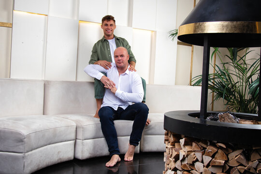 Happy gay couple relaxing on the sofa at home. Two handsome men.