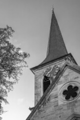  Clock Tower from an old Protestant church with trees framing the shot and rooster sitting on top shot in the evening in summer in black and white