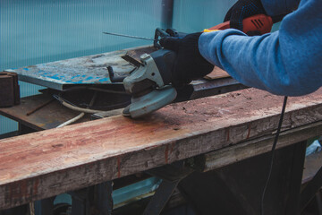 a man is grinding a board. Removing old paint from boards. Carpentry work.