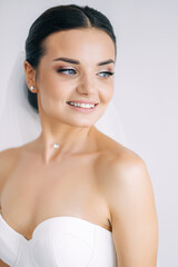 young cheerful bride in a wedding dress in a white room waiting for the groom.