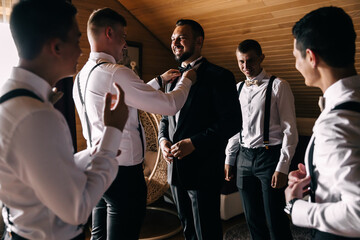 a friend straightens the groom's bow tie on his shirt, morning preparation for the holiday