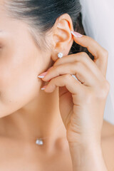 bride puts on a diamond earring for wedding celebrations - 510378762