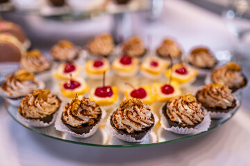 Delicious sweet desserts with butter cream and cherries.