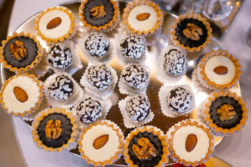 Creamy desserts decorated with nuts on a large plate on the festive table