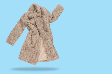 Beige faux fur coat, levitates, as if dancing, on a blue background