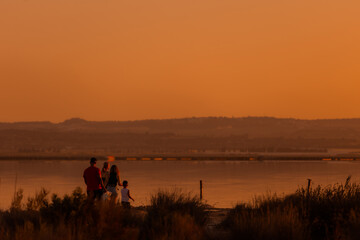 Fototapeta na wymiar People at the orange sunset by the lake