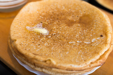 hot golden pancakes made from grain flour in kitchen while cooking on pans and on plate