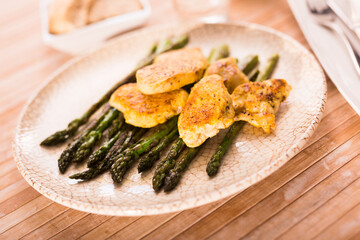 cooked dish. Chicken nuggets with green asparagus on plate