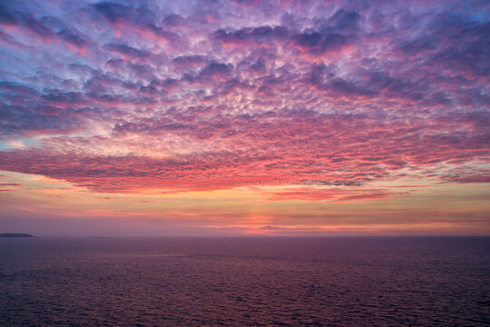 Coucher de soleil sur la mer vue des côtes de Bretagne. Nuages et océan entre le violet et le orange. 