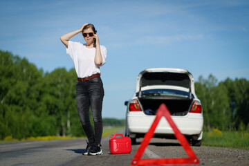 Driver standing with empty fuel canister against car background.