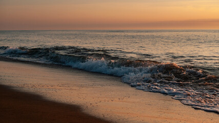 Fototapeta na wymiar Sunrise over the ocean with gentle waves coming ashore