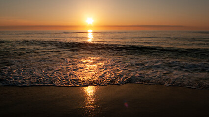 Sunrise over the ocean with gentle waves coming ashore