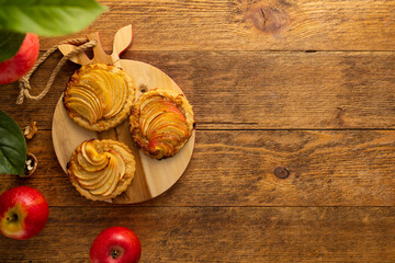 Mini Apple pie tartlets with walnut on wooden table. Delicious dessert for autumn winter dinner.Top view.