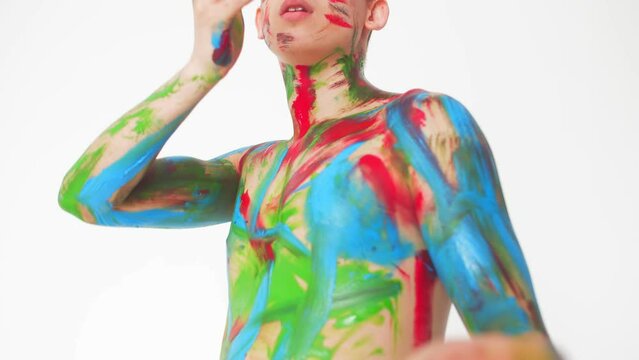 Plastic European guy in paint on a naked body dancing on a white background, The concept of art and creativity