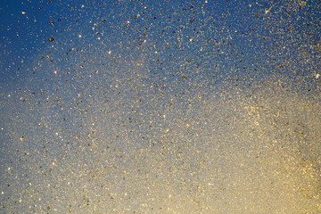Bright splashes of the water fountain against the blue sky. Abstract color composition in sunshine backlight.