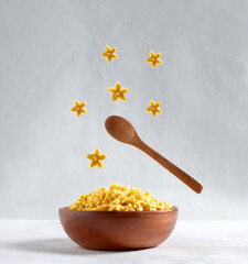 Wooden bowl with star corn flakes on gray background. Food levitation. Good morning card.