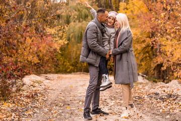 Obraz premium Young happy family while walking in the autumn park.