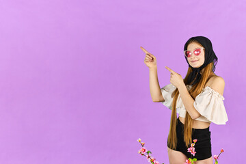 Young long hair woman shows something, point finger left at blue studio background. Girl pointing fingers left and smiling, showing advertisement.