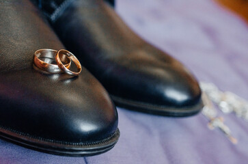 Fototapeta na wymiar wedding rings lie on black men's shoes