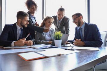 Group of young modern people in formalwear smiling and discussing something while working in the modern office